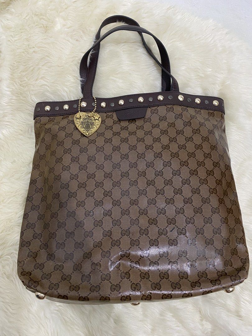 Gucci Bag (Category: Luxury Bags & Wallets) located in San Antonio. Submitted by clinicallycute_. (Listing ID 1456176769, Image 1). Description: - Gucci tote bag with code - Classic GG monogram canvas - Brown leather trim and handles - Decorative heart charm with Gucci logo - Studded details along the top edge - Interior zip pocket - Made in Italy.
