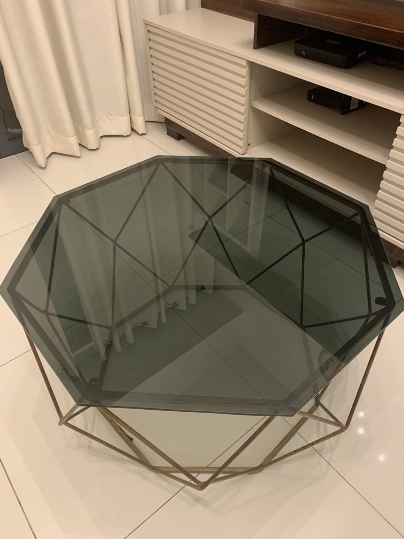 Octagonal Glass Top Coffee Table with Geometric Metal Base (Category: Tables & Sets) located in Taguig. Submitted by cheonsaper27095 (Listing ID 1456090926, Image 2). Description: - Octagonal coffee table - Dark tinted glass top - Geometric metal frame base - Brassy gold tone finish - Modern, minimalist design - Ideal for living rooms or lounges.