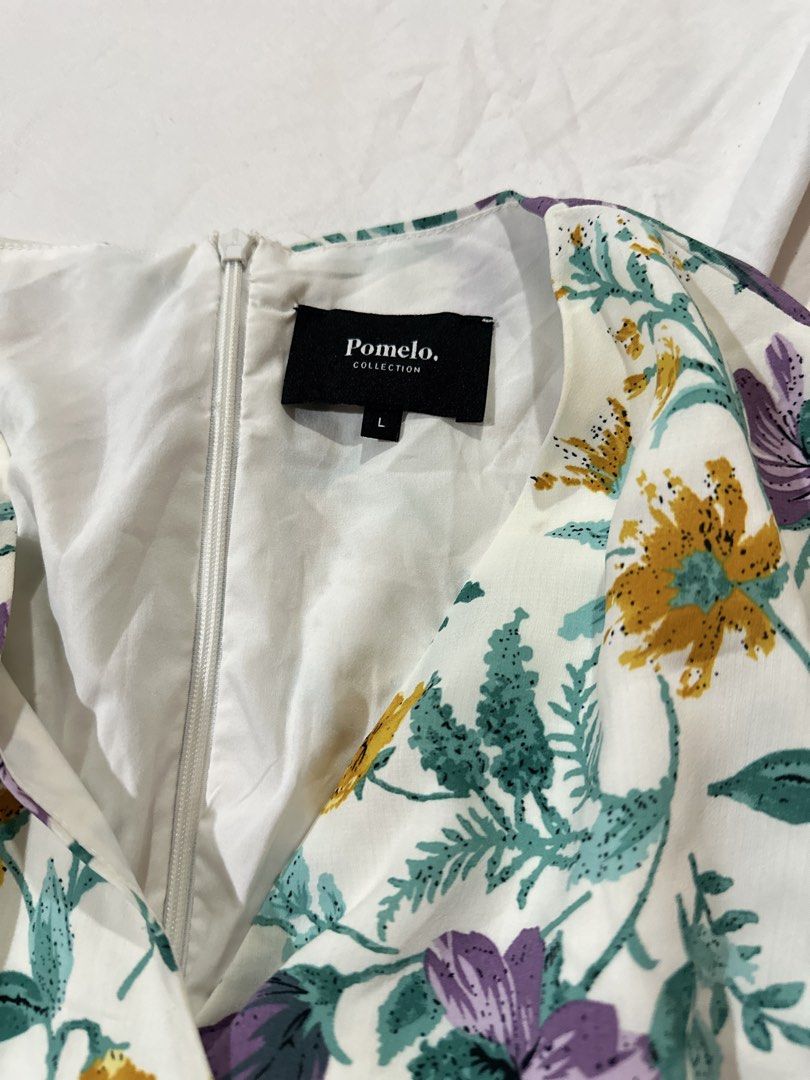 Pomelo Floral Wrap Dress Size L (Category: Dresses) located in Quezon City. Submitted by aleezy (Listing ID 1456098342, Image 2). Description: - White wrap dress with a vibrant floral print - Features purple, yellow, and green flowers - Long sleeves with ruffled cuffs - Zipper closure at the back - Ruffled hemline for a stylish touch - Ideal for casual outings or events.