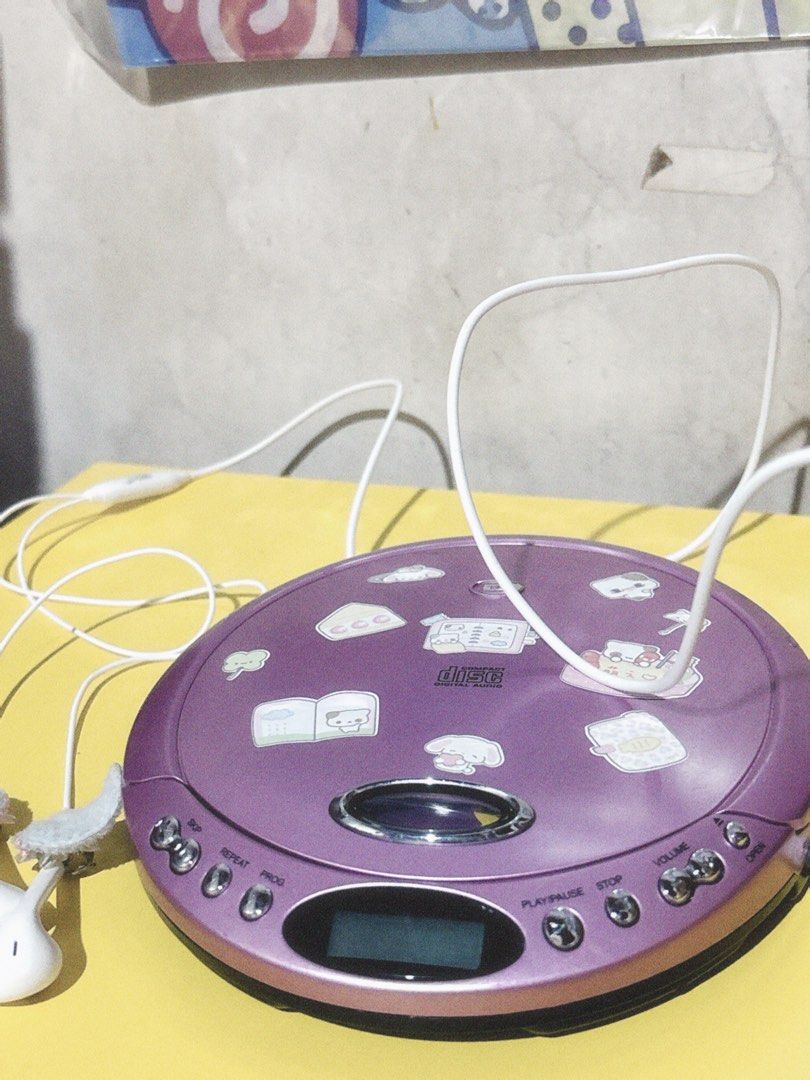 Purple Portable CD Player (Category: Portable Music Players) located in Manila. Submitted by meloopsy (Listing ID 1456074219, Image 2). Description: - Purple portable CD player - Includes white earphones - Plays CDs - Buttons: Play, Pause, Stop, Repeat, Program - Small LCD screen for easy viewing - Ideal for listening to music anywhere - Note: Some stickers are present on the lid.