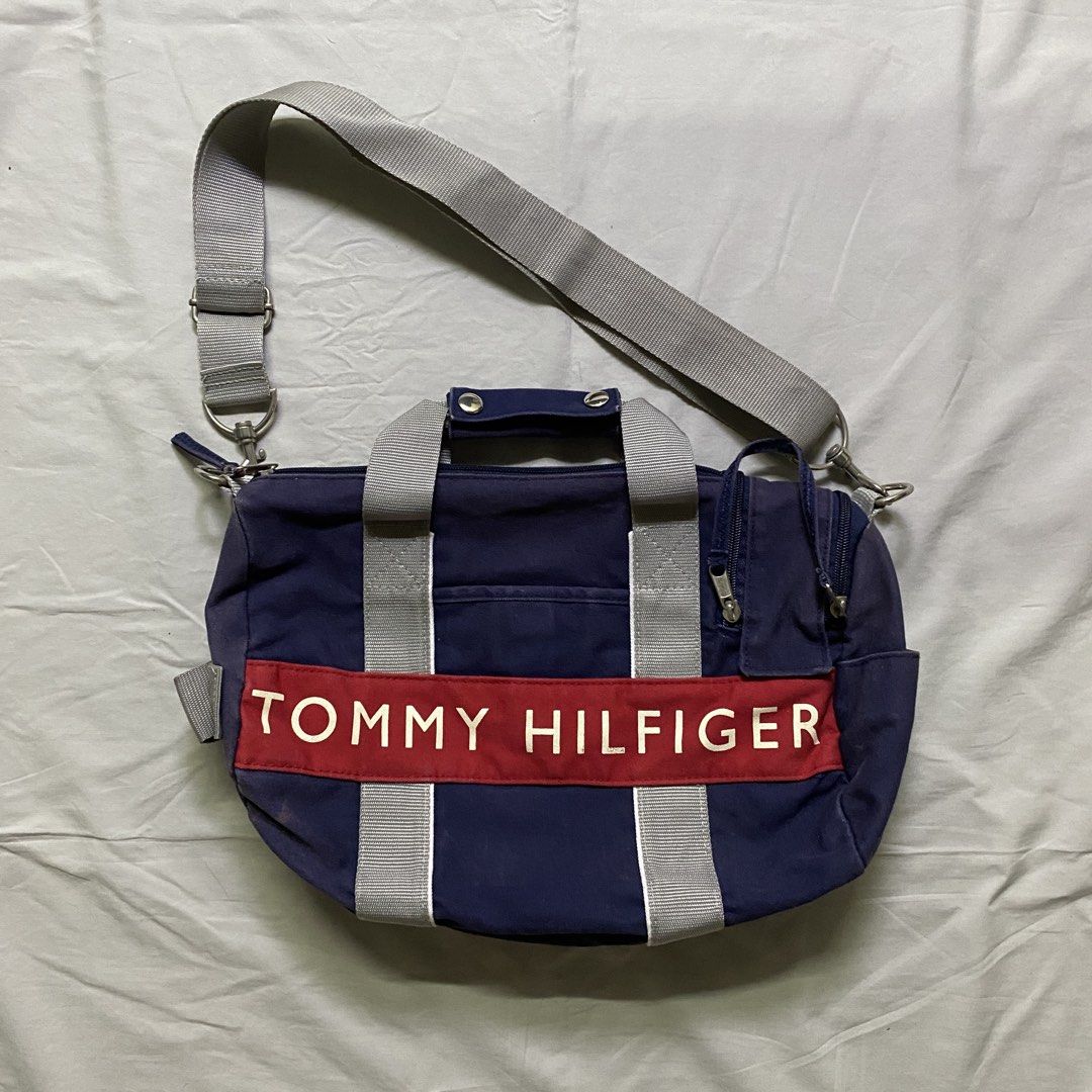 Tommy Hilfiger Navy Blue Duffle Bag with Shoulder Strap (Category: Shoulder Bags) located in Marikina City. Submitted by beeeekenneth (Listing ID 1456140868, Image 1). Description: - Navy blue Tommy Hilfiger duffel bag - Signature red and white logo band on front - Top handles and detachable shoulder strap - Zipped main compartment - Front zip pocket - Small side pockets - Ideal for gym or weekend trips -sunfade issue Location: Marikina + we can 