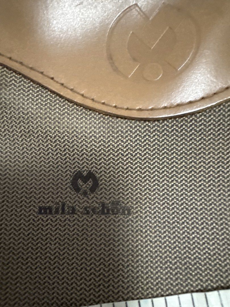 2027 Mila Schön Pouch Bag (Category: Luxury Bags & Wallets) located in Silang. Submitted by sari2bilina (Listing ID 1456330390, Image 3). Description: - Brown Mila Schön pouch - All-over monogram print - Leather handle and trim - Zipper closure - 'MENARD' logo inside - Approx. 6 inches in height.