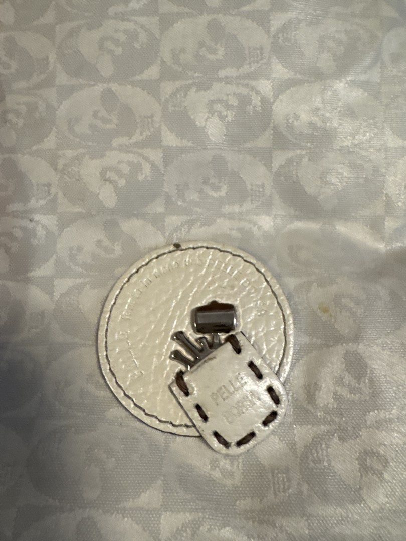 2027 Pelle Borse White Monogram Shoulder Bag (Category: Luxury Bags & Wallets) located in Silang. Submitted by sari2bilina (Listing ID 1456368815, Image 3). Description: - Stylish white shoulder bag - Features a repeating monogram pattern - Elegant leather trim - Secure circular clasp closure - Adjustable strap for comfort - Dimensions: Approximately 12 inches wide x 10 inches tall - Interior lining: Grey - Includes a small leather tag with brand