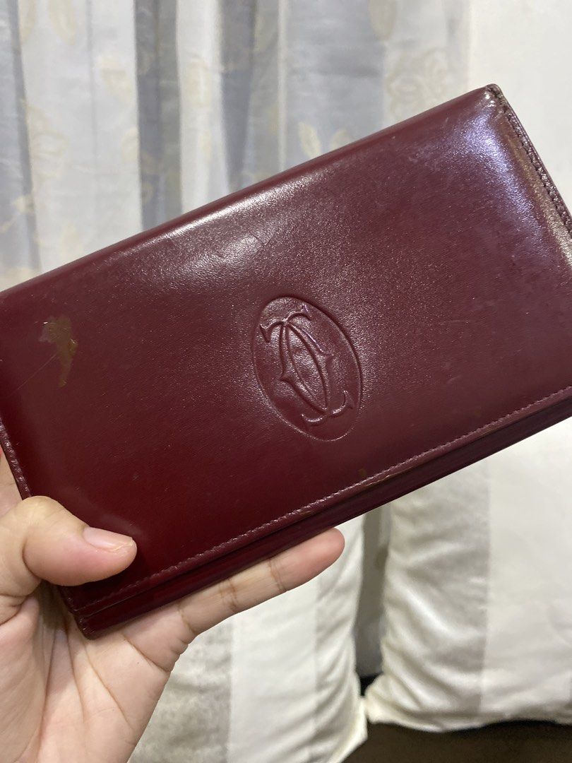 Cartier Burgundy Leather Long Wallet (Category: Wallets & Card holders) located in Cadiz. Submitted by saveandstyleph (Listing ID 1456345416, Image 2). Description: - Burgundy leather long wallet from Cartier - Iconic Cartier logo embossed on the front - Secure clasp closure - Multiple interior card slots - Minor scuffs on exterior leather - A classic and essential accessory.