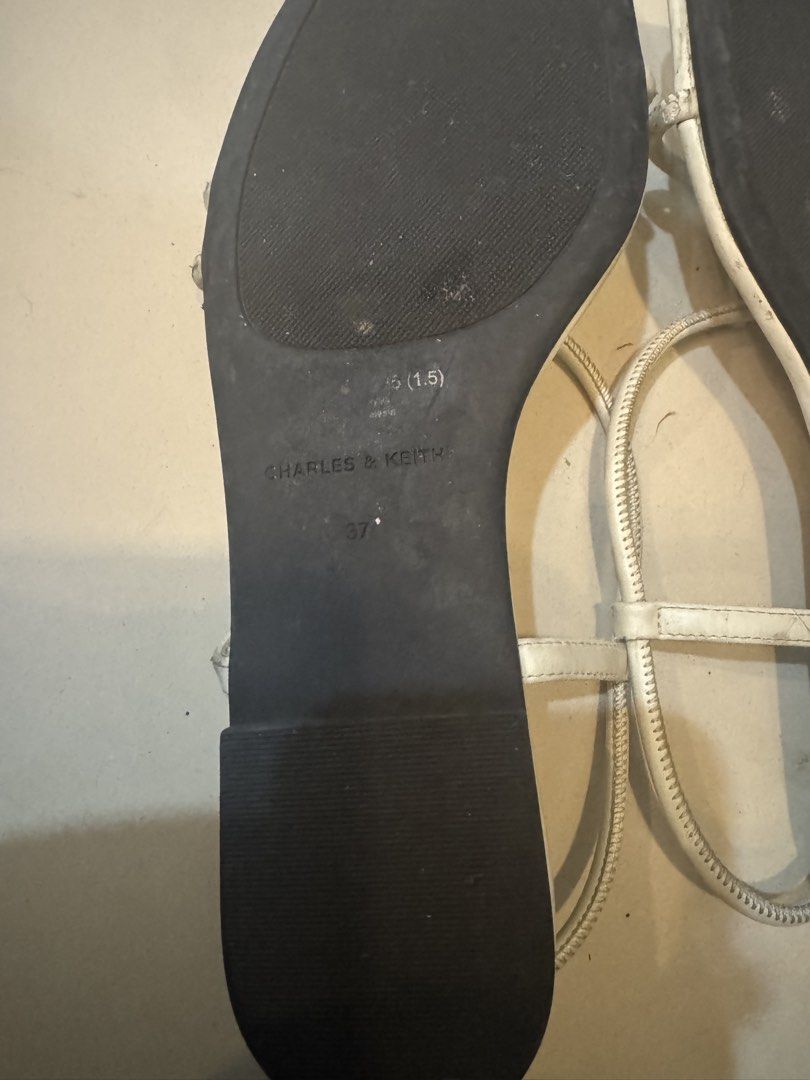 Charles & Keith White Strappy Flat Sandals Size 37 (Category: Flats & Sandals) located in Manila. Submitted by decluterthings888 (Listing ID 1456361195, Image 3). Description: - Brand: Charles & Keith - Color: White - Style: Strappy Flat Sandals - Size: 37 - Condition: Gently used with some signs of wear on insoles and soles - Features: Thin, delicate straps; adjustable buckle closure - Occasion: Ideal for casual outings.