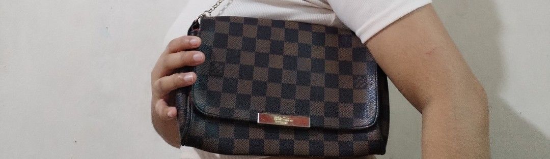 Louis Vuitton Damier Ebene Canvas Shoulder Bag (Category: Luxury Bags & Wallets) located in Quezon City. Submitted by hesperiana (Listing ID 1456315997, Image 1). Description: UKAY (not sure if legit or not) - Classic Louis Vuitton shoulder bag in Damier Ebene canvas. - Iconic checkered pattern. - Elegant gold chain strap. - Secure metal clasp closure with Louis Vuitton Paris engraving. - Luxurious red interior lining. - Versatile for everyday us