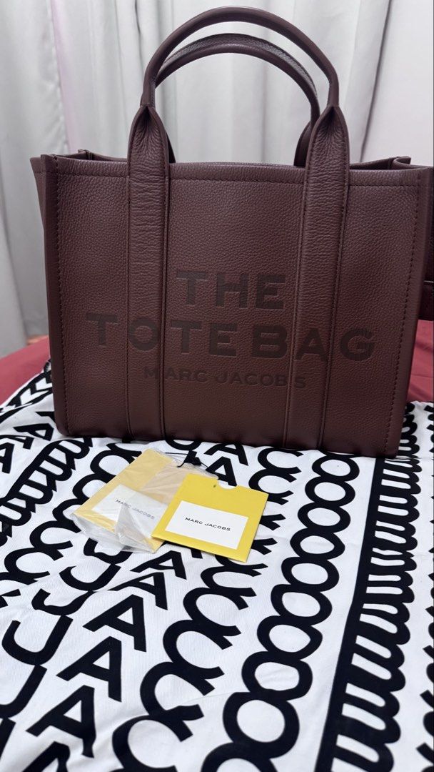 Marc Jacobs The Tote Bag (Category: Luxury Bags & Wallets) located in Batangas. Submitted by kringkring. (Listing ID 1456249359, Image 1). Description: - Authentic Marc Jacobs The Tote Bag - Color: Deep Brown - Material: Genuine Leather - Closure: Zip main compartment - Interior: Slip pockets and a zip pocket - Condition: Brand new with original tags - Ideal for: Everyday use.