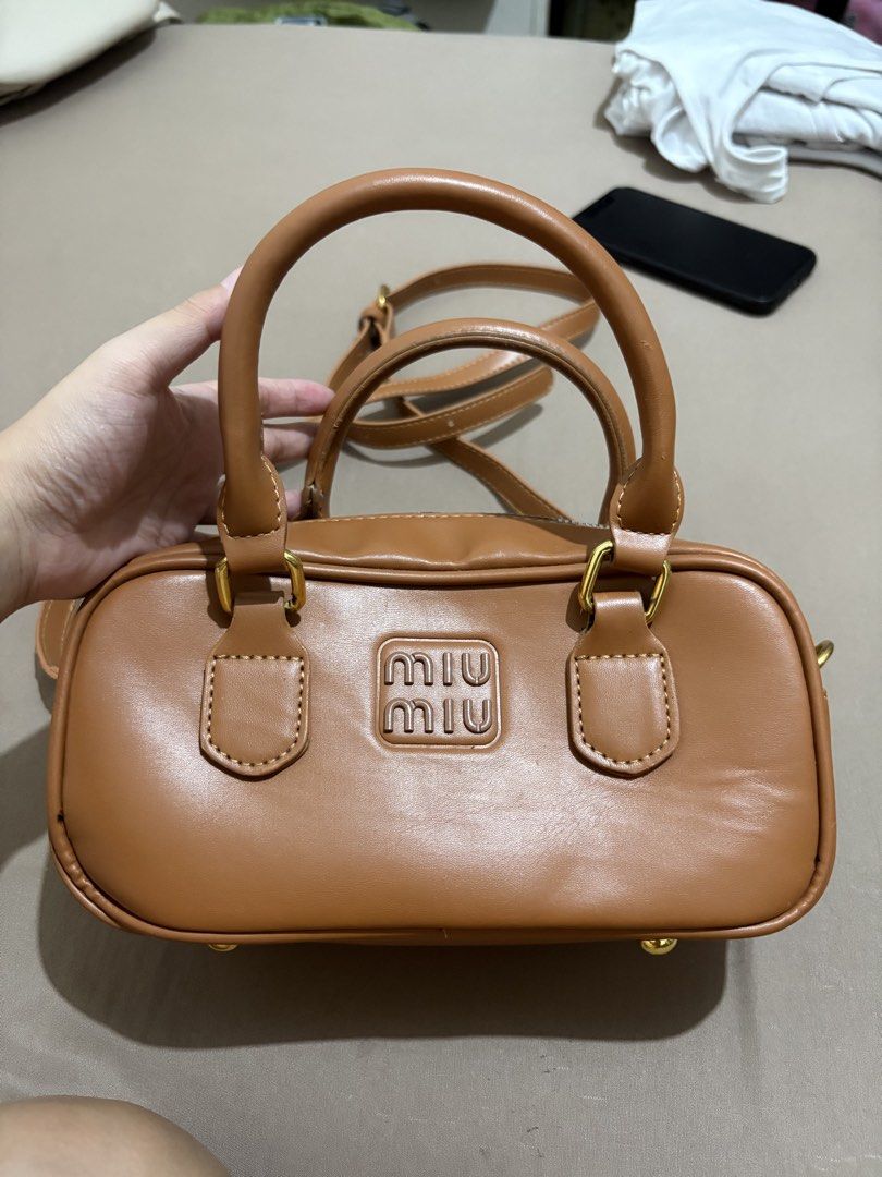 Miu Miu Brown Leather Mini Boston Bag (Category: Luxury Bags & Wallets) located in Marilao. Submitted by lovely.loot (Listing ID 1456266246, Image 1). Description: - Brown leather mini boston bag - Top handles and detachable shoulder strap - Secure zipper closure - Gold hardware details - Compact black interior - Ideal for carrying essentials.