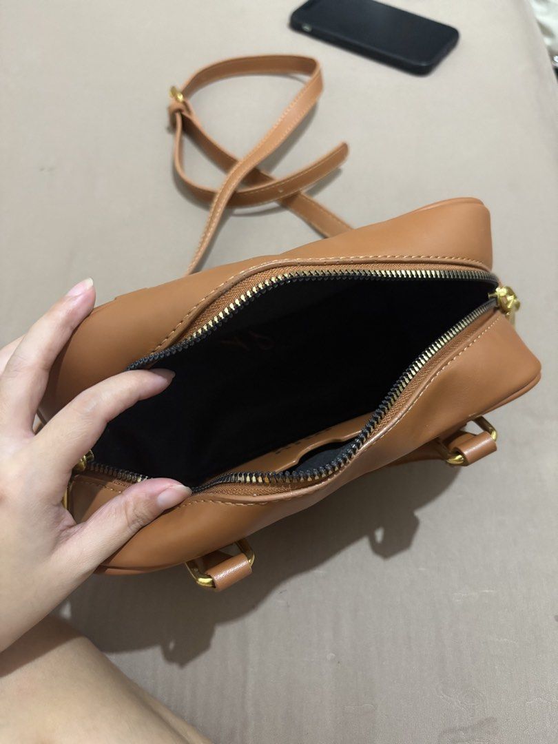 Miu Miu Brown Leather Mini Boston Bag (Category: Luxury Bags & Wallets) located in Marilao. Submitted by lovely.loot (Listing ID 1456266246, Image 2). Description: - Brown leather mini boston bag - Top handles and detachable shoulder strap - Secure zipper closure - Gold hardware details - Compact black interior - Ideal for carrying essentials.