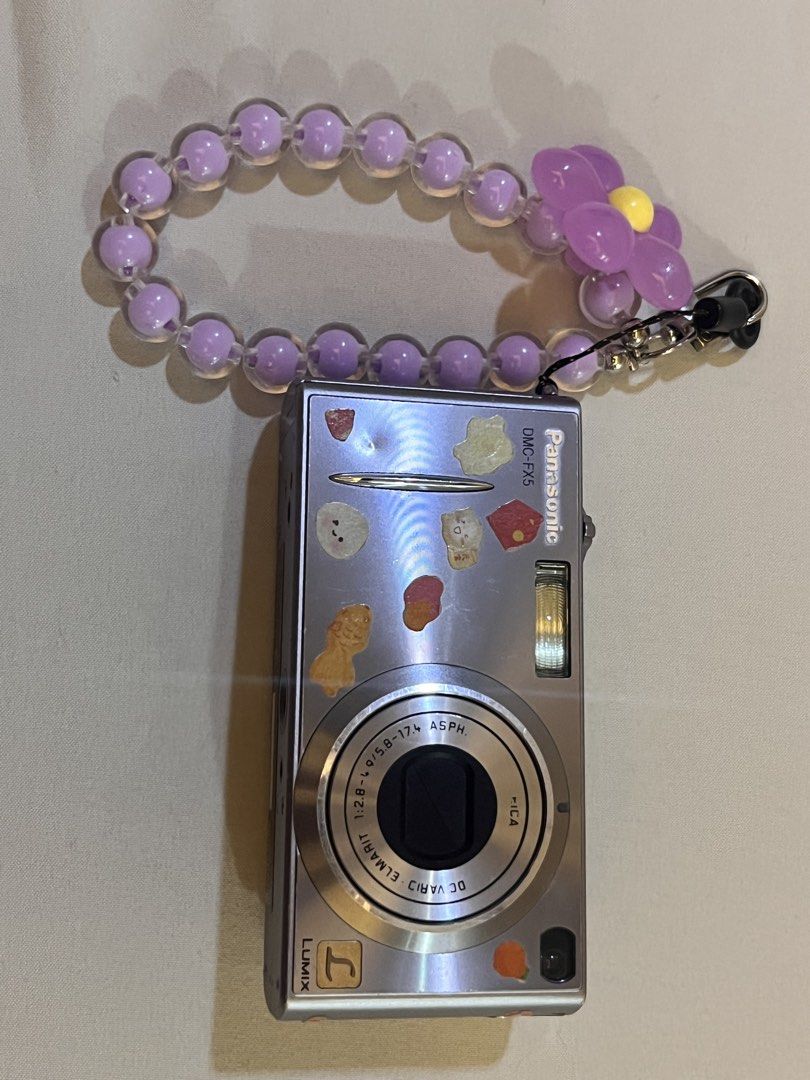 Panasonic Lumix DMC-FX5 Digital Camera with Charm Strap (Category: Cameras) located in Manila. Submitted by cuddleblue (Listing ID 1456352052, Image 1). Description: - Silver Panasonic Lumix DMC-FX5 digital camera - Battery & charger included - Comes with a cute purple beaded charm strap with a flower - No SD card included - Ideal for casual pics Issues: has battery issues. turns on/off on its own .