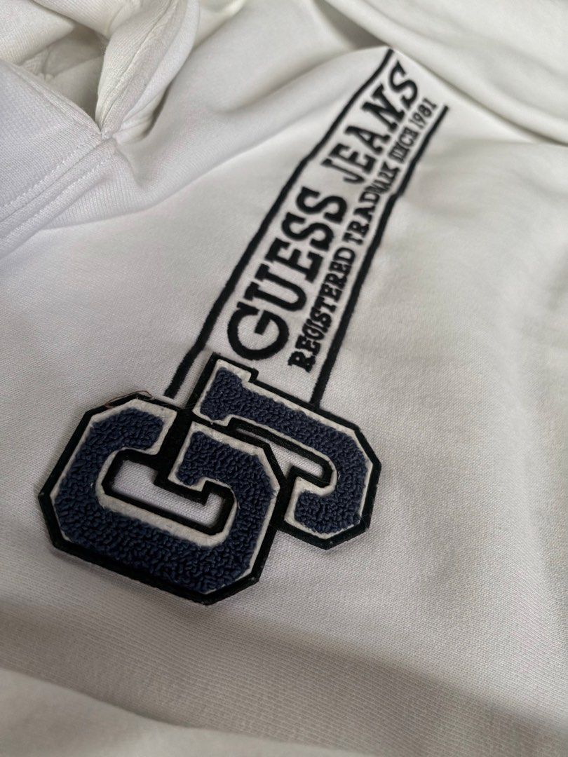 White Guess Jeans Hoodie (Category: Hoodies) located in Manila. Submitted by izzmya (Listing ID 1456238011, Image 2). Description: - Can fit s-m - White Guess Jeans hoodie - Features classic 'GJ' logo with 'Guess Jeans Registered Trademark Since 1981' text - Front kangaroo pocket - Note: Some light yellowing/stains inside the hoodie area.