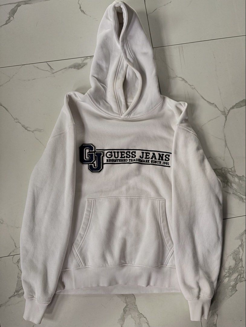 White Guess Jeans Hoodie (Category: Hoodies) located in Manila. Submitted by izzmya (Listing ID 1456238011, Image 1). Description: - Can fit s-m - White Guess Jeans hoodie - Features classic 'GJ' logo with 'Guess Jeans Registered Trademark Since 1981' text - Front kangaroo pocket - Note: Some light yellowing/stains inside the hoodie area.