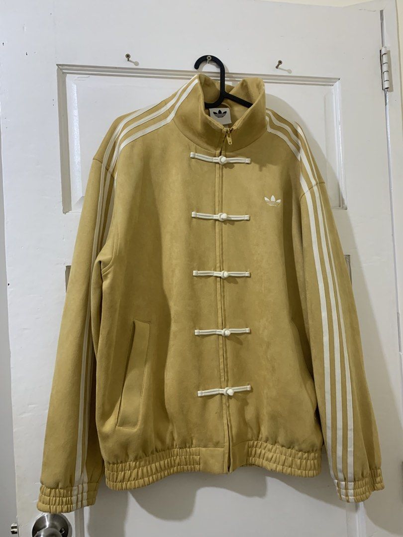 Adidas Yellow TANG CNY Jacket (Category: Coats, Jackets and Outerwear) located in Bacoor. Submitted by ianmagdale (Listing ID 1456539883, Image 3). Description: - Eye-catching yellow Adidas jacket - Suede-like material - Iconic three stripes on the sleeves - Unique Chinese frog button closures down the front - Additional zipper closure for versatility - Comfortable ribbed cuffs and hem - Perfect statement piece to elevate any outfit.
