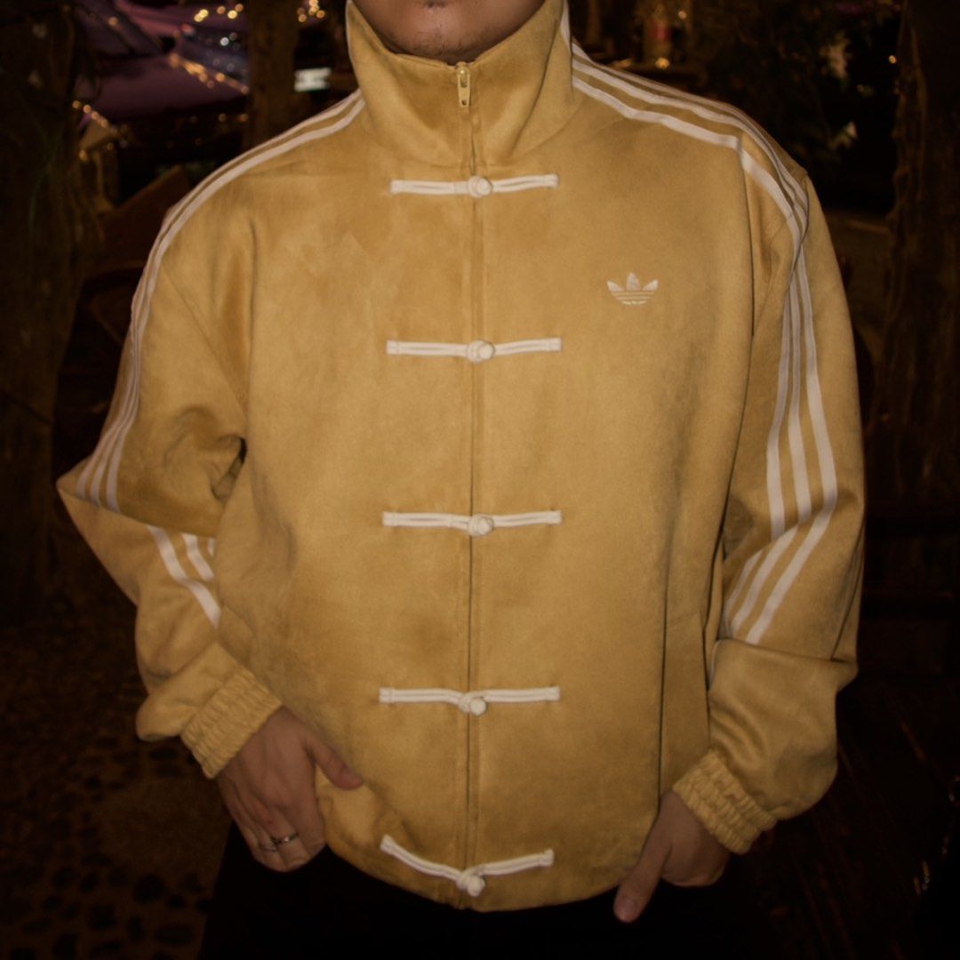 Adidas Yellow TANG CNY Jacket (Category: Coats, Jackets and Outerwear) located in Bacoor. Submitted by ianmagdale (Listing ID 1456539883, Image 1). Description: - Eye-catching yellow Adidas jacket - Suede-like material - Iconic three stripes on the sleeves - Unique Chinese frog button closures down the front - Additional zipper closure for versatility - Comfortable ribbed cuffs and hem - Perfect statement piece to elevate any outfit.