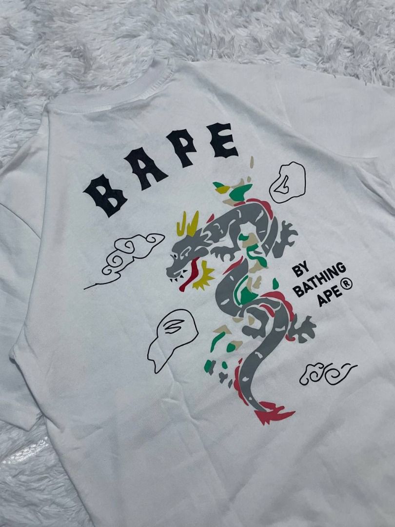 BAPE By Bathing Ape Dragon T-Shirt White (Category: Tshirts & Polo Shirts ) located in Caloocan City. Submitted by shop_tuffgoods (Listing ID 1456517307, Image 1). Description: - White BAPE T-shirt - Size: S - Features a striking dragon graphic on the back - Includes smaller graphics on the front - Comes with original tags attached - Ideal for fans of streetwear fashion - Width - 20" - Length - 28".