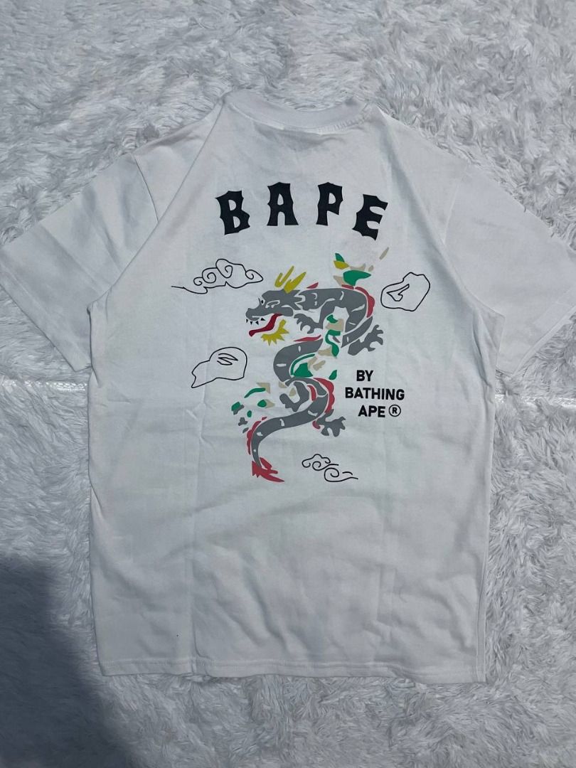 BAPE By Bathing Ape Dragon T-Shirt White (Category: Tshirts & Polo Shirts ) located in Caloocan City. Submitted by shop_tuffgoods (Listing ID 1456517307, Image 2). Description: - White BAPE T-shirt - Size: S - Features a striking dragon graphic on the back - Includes smaller graphics on the front - Comes with original tags attached - Ideal for fans of streetwear fashion - Width - 20" - Length - 28".