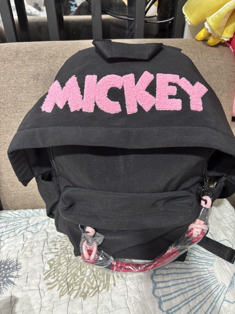 Black Mickey Mouse Backpack with Pink Accents (Category: Backpacks) located in Mexico. Submitted by 3everything (Listing ID 1456483542, Image 2). Description: - Cute black backpack with pink 'MICKEY' lettering - Front pocket and side pockets for extra storage - Light beige interior with a small pocket - Adjustable straps for a comfortable fit - Ideal for school or everyday use - parang nakahoodie yung bag.