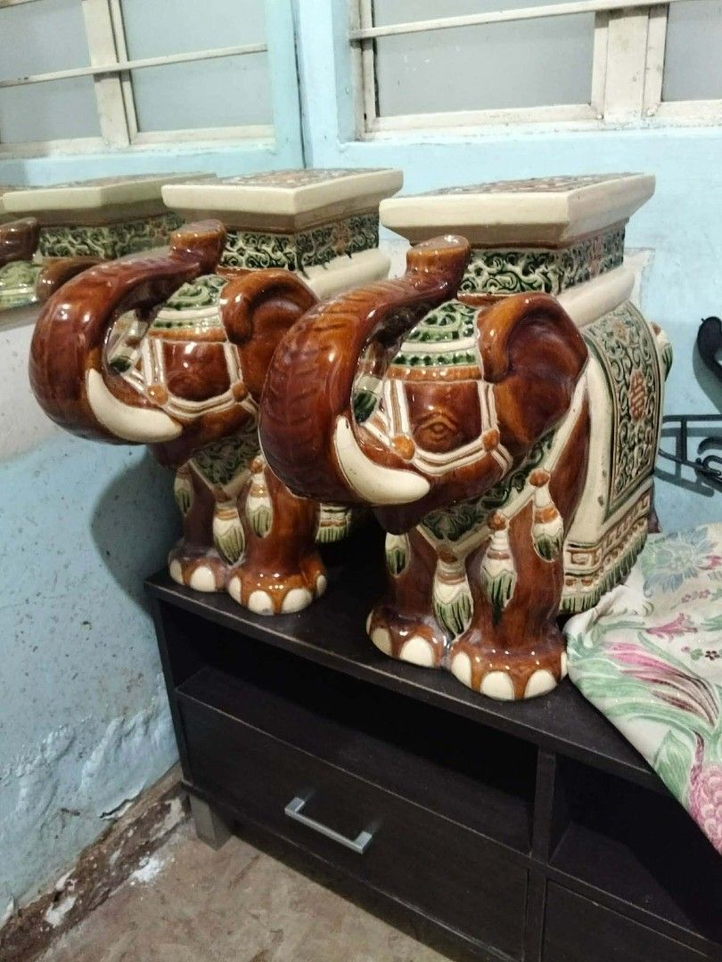 Ceramic Elephant Stool Side Table Plant Stand (Category: Other Home Decor) located in Taguig. Submitted by eeng5 (Listing ID 1456422940, Image 2). Description: - Unique ceramic elephant stools - Versatile: use as side tables or plant stands - Sturdy and heavy construction - Brown elephants with detailed green & white saddle blankets - Cream-colored square top - Perfect for adding a unique decorative touch to your home.
