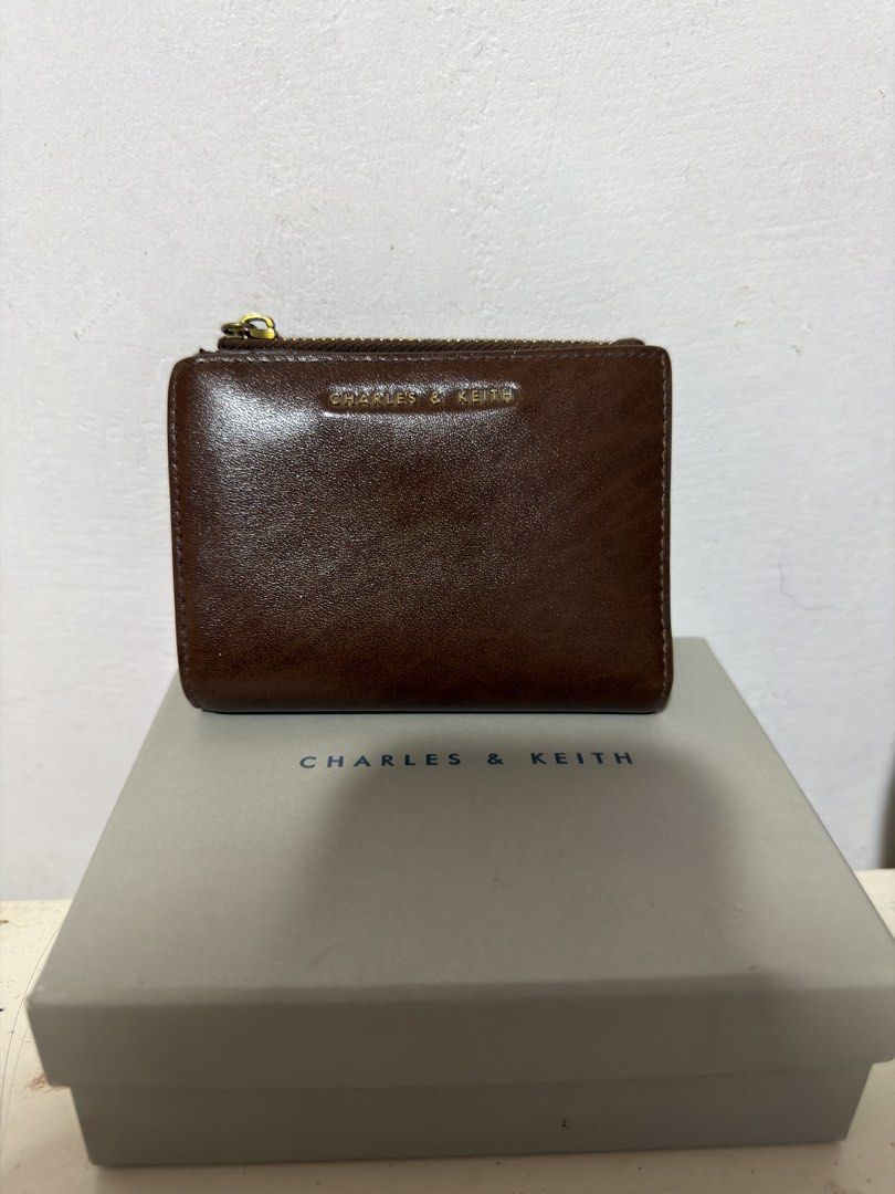 Charles & Keith Brown Leather Bi-fold Wallet (Category: Wallets & Card holders) located in Tuguegarao City. Submitted by pavlene (Listing ID 1456542643, Image 1). Description: - Brand: Charles & Keith - Material: Brown Leather - Style: Bi-fold wallet - Features: Top zip compartment, ample card slots, snap button closure - Condition: Good for everyday use - Includes: Original box and tag.