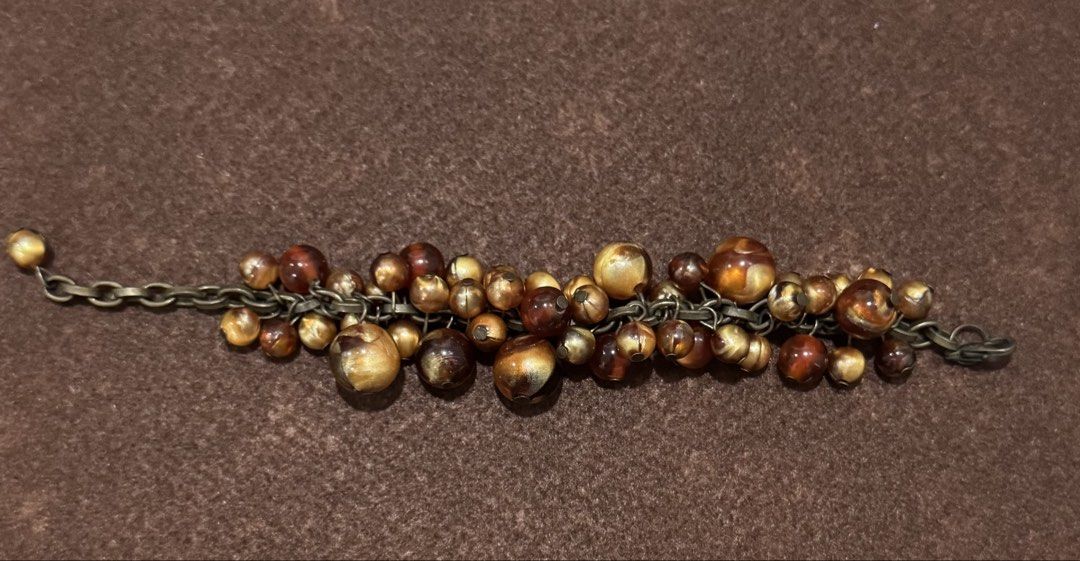 Chunky Beaded Charm Bracelet Gold Brown Tones (Category: Bracelets) located in Quezon City. Submitted by kcapi (Listing ID 1456561188, Image 1). Description: - Chunky statement bracelet - Mixed beads in gold and brown tones - Features both translucent and opaque beads - Dark metal chain - Adds flair to any outfit.