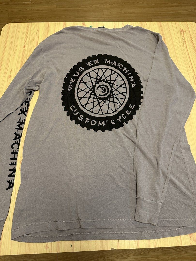 Deus Ex Machina Venice Custom Cycle Long Sleeve Tee (Category: Tshirts & Polo Shirts ) located in Quezon City. Submitted by mancave_stuff (Listing ID 1456523422, Image 2). Description: - Deus Ex Machina long sleeve t-shirt -Color: Grey - Size: Medium -W21” x L29” - Chest: 'Deus Ex Machina Venice CA' patch - Back: Large 'Deus Ex Machina Custom Cycle' graphic - Sleeve: Text graphic down the left sleeve .
