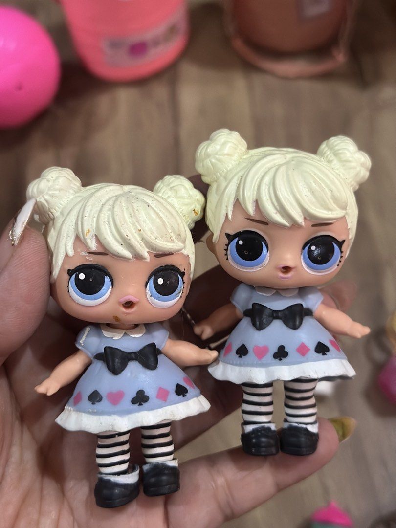 LOL Surprise Dolls with Accessories (Category: Kids Toys) located in Baguio. Submitted by cherylcaps95 (Listing ID 1456484453, Image 2). Description: - Two LOL Surprise dolls included. - Dolls have blonde hair styled in buns. - Each doll wears a blue dress with card suit patterns. - Features black and white striped socks. - Accessories include two drink bottles and two gem-shaped purses. - Ideal for LOL Surprise collectors and playtime fun..