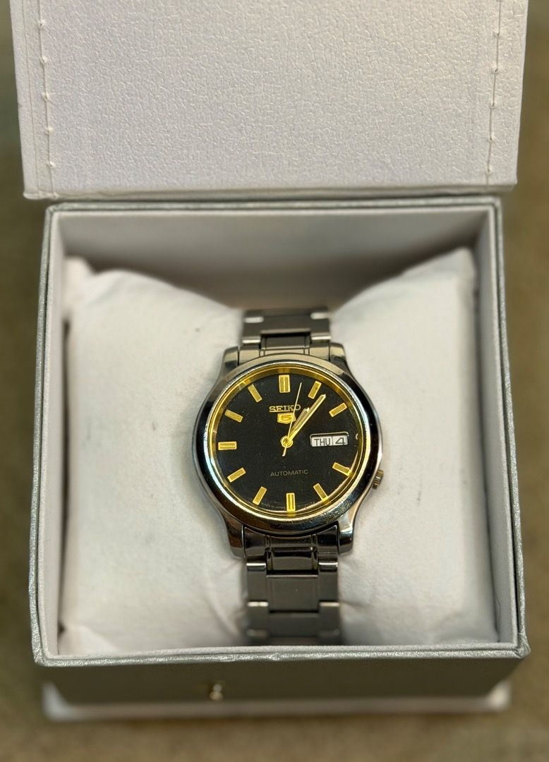 SEIKO 5 "BLACK GOLD" (Category: Luxury Watches) located in Andop. Submitted by john_karl23 (Listing ID 1456427385, Image 1). Description: Seiko 5 Vintage Automatic Watch Seiko 5 Vintage Automatic Ref. 7S26-02J0 A dependable Japanese watch with a 37 mm stainless steel case, black dial touched with gold, and a handy day-date display. Powered by Seiko’s trusted 7S26 automatic movement, it’s built for everyday wear with timeless style. 📌Newly Servic