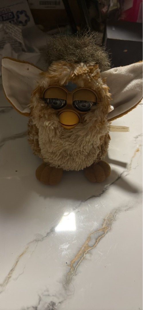 Vintage Furby Toy (Category: Interactive Toys) located in Pasig City. Submitted by rarelion_f7ba92 (Listing ID 1456578877, Image 2). Description: - Classic Furby toy - Color: Light brown and tan - Features: Big blue eyes, fuzzy ears - Condition: Fur is a bit worn in places - Ideal for: Collectors, electronics toy enthusiasts, display .