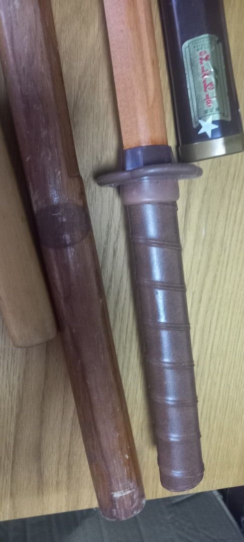 Wooden Practice Sword with Sheath (Category: Musical Instruments) located in Manila. Submitted by fmpc7878 (Listing ID 1456517857, Image 3). Description: - Wooden practice sword - Includes two saya (sheaths): one dark brown, one light wood - Tsuka (handle) wrapped in brown material - Dark brown saya features a 'MADE IN KOREA' label - Suitable for display or practice Take all Price for 500 AS IS ABUSED CONDITION WITH ITS FLAWS.