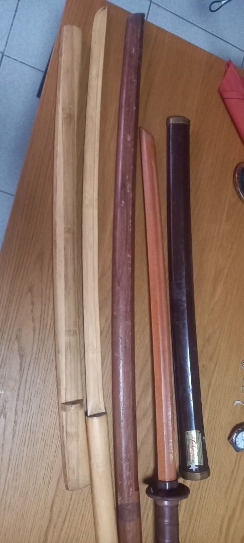 Wooden Practice Sword with Sheath (Category: Musical Instruments) located in Manila. Submitted by fmpc7878 (Listing ID 1456517857, Image 1). Description: - Wooden practice sword - Includes two saya (sheaths): one dark brown, one light wood - Tsuka (handle) wrapped in brown material - Dark brown saya features a 'MADE IN KOREA' label - Suitable for display or practice Take all Price for 500 AS IS ABUSED CONDITION WITH ITS FLAWS.