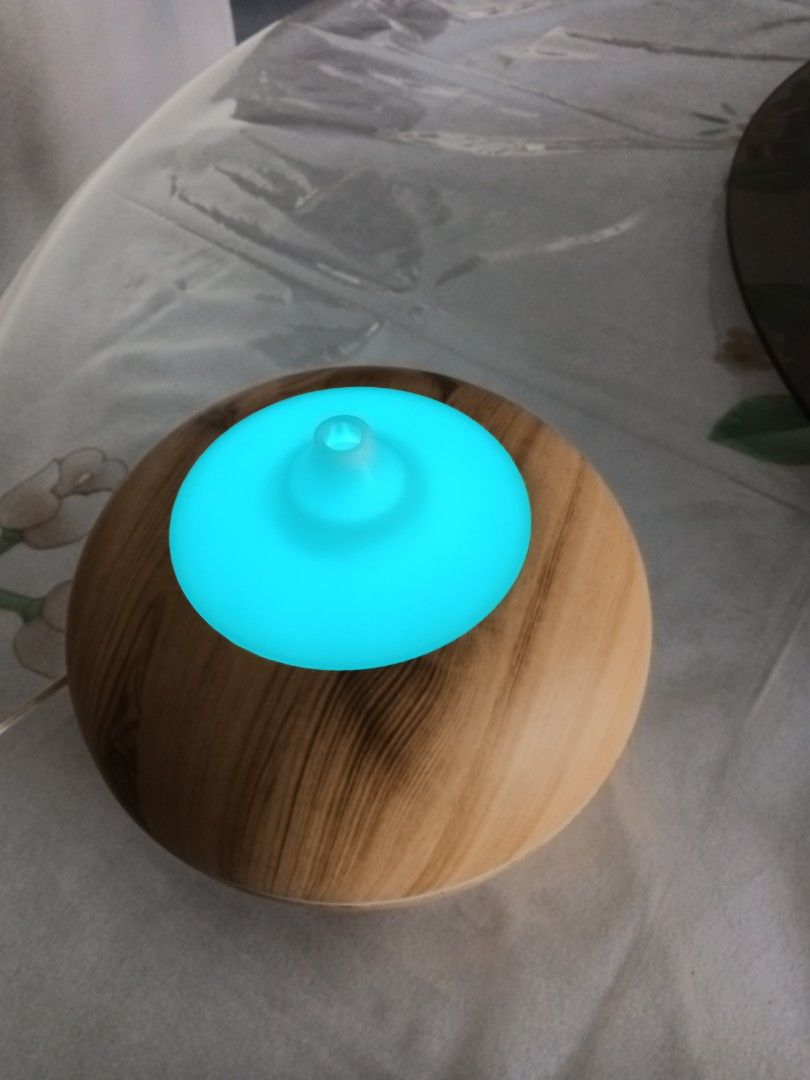 Aroma diffuser (Category: Home Fragrance) located in Singapore. Submitted by wqcrecycler (Listing ID 1453338634, Image 2). Description: - Aroma diffuser with a stylish wood-grain top and white base, - variable colourful light - Comes with the necessary power adapter. - In good working condition. - Perfect for home fragrance and creating a relaxing atmosphere. - Meetups available in Bishan..