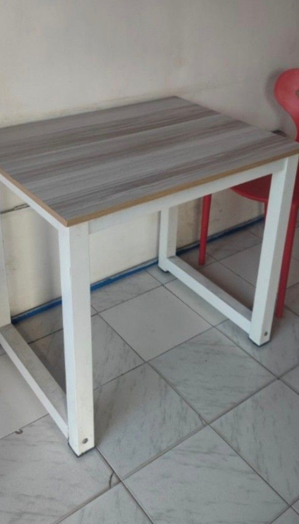Compact Square Table with Wood Grain Top and White Frame (Category: Tables & Sets) located in Caloocan City. Submitted by aceaceyye (Listing ID 1453322674, Image 1). Description: 80x60cm size Heavy duty Sturdy Item is in good condition For pick up or via Lalamove Location: Metro Royale, Burgos, Montalban, Rizal (6pcs) - Note: Red chairs shown are not included..
