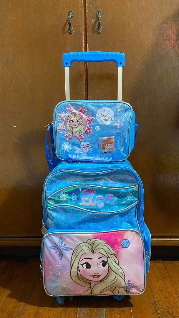 Disney Frozen Elsa Rolling Backpack with Lunch Bag (Category: Babies & Kids Fashion) located in Pasig City. Submitted by auntchuch (Listing ID 1453354960, Image 1). Description: - Adorable blue rolling backpack featuring Elsa from Disney's Frozen. - Comes with a matching lunch bag that securely attaches to the front. - Equipped with wheels and a retractable handle for effortless portability. - Comes with a waterproof bag cover - Spacious interior