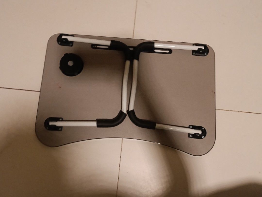 Foldable table (Category: Tables & Sets) located in Singapore. Submitted by ambi_swag (Listing ID 1453405672, Image 2). Description: - Foldable laptop table with a stylish wood-grain finish. - Perfect for use in bed, on the sofa, or anywhere you need a convenient surface. - Legs fold flat for easy storage and portability. - Features a built-in slot for tablets or phones. - Includes a convenient cup holder. - Versatile and practical for work, stud