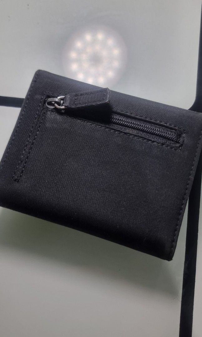 GUESS women's compact trifold wallet (Category: Wallets & Card holders) located in San Pedro. Submitted by elevens_online_thrift_shop (Listing ID 1453298517, Image 3). Description: ​Brand: GUESS ​Style: Vintage / Y2K-era flap wallet (trifold or bifold silhouette) ​Material: Black durable fabric/canvas upper with a metal logo plate on the main flap ​Features: Typically includes card slots, an ID window, a bill compartment, and a snap button closur