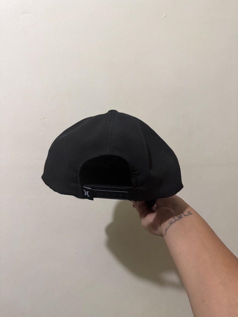 Hurley Black Snapback Cap with Rope Detail (Category: Caps & Hats) located in Manila. Submitted by mrtndmnc (Listing ID 1453401488, Image 2). Description: - Black Hurley snapback cap - Rope detail across the brim - Embroidered palm tree and golf flag graphic on the front - Perforated sides for enhanced breathability - Adjustable snapback closure for a custom fit - Ideal for everyday casual wear.