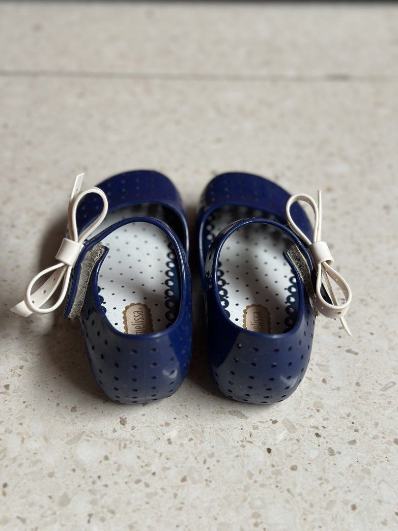 Mini Melissa Navy Blue Flats with White Bows (Category: Babies & Kids Fashion) located in Manila. Submitted by alexandrap74256 (Listing ID 1453355228, Image 2). Description: - Cute navy blue jelly flats - Features a perforated design all over - Adorned with a sweet white bow on each shoe - Ideal for casual wear or beach days - Easy slip-on and off design Size US 7 (14 cm) - Perfect for little girls.