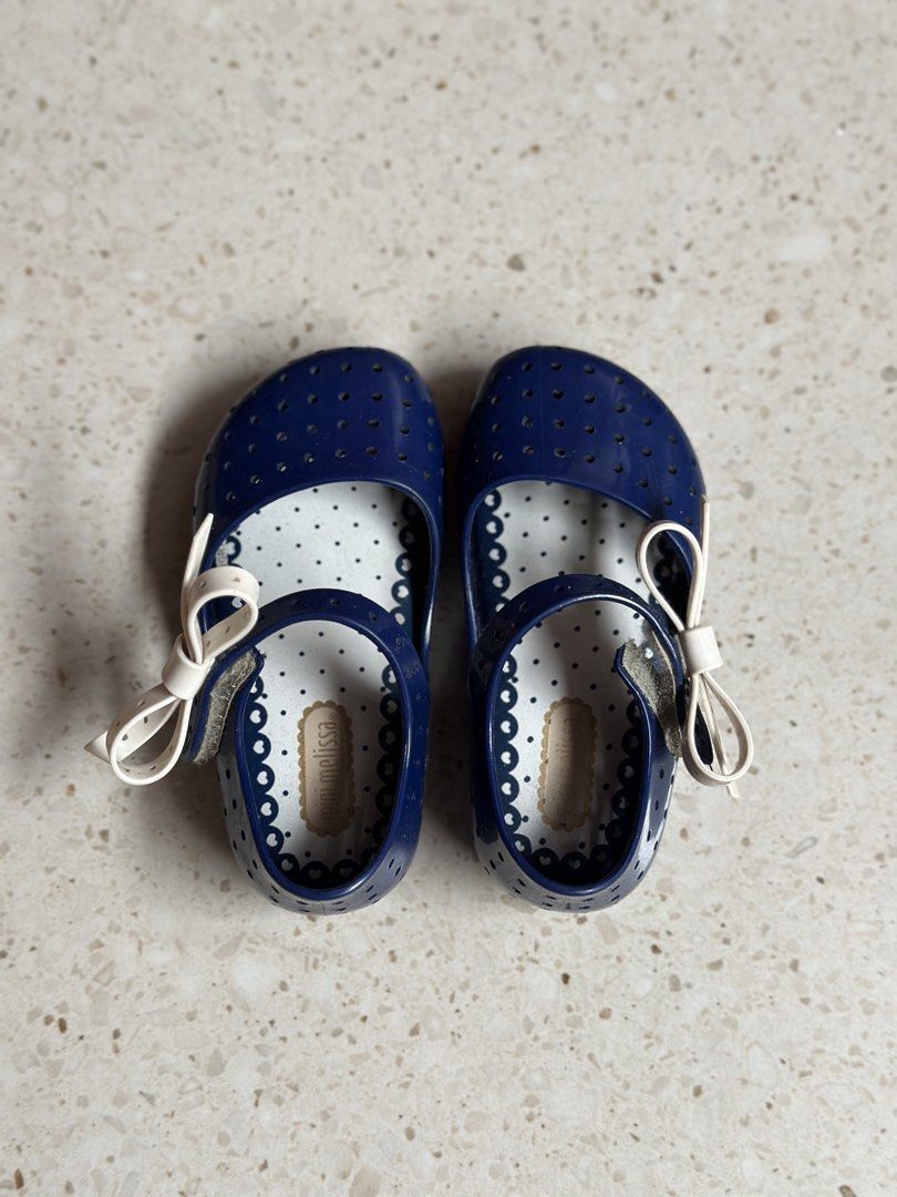 Mini Melissa Navy Blue Flats with White Bows (Category: Babies & Kids Fashion) located in Manila. Submitted by alexandrap74256 (Listing ID 1453355228, Image 1). Description: - Cute navy blue jelly flats - Features a perforated design all over - Adorned with a sweet white bow on each shoe - Ideal for casual wear or beach days - Easy slip-on and off design Size US 7 (14 cm) - Perfect for little girls.