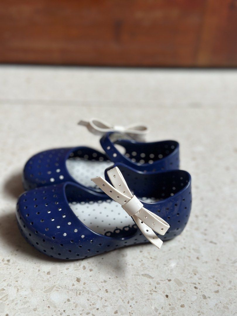 Mini Melissa Navy Blue Flats with White Bows (Category: Babies & Kids Fashion) located in Manila. Submitted by alexandrap74256 (Listing ID 1453355228, Image 3). Description: - Cute navy blue jelly flats - Features a perforated design all over - Adorned with a sweet white bow on each shoe - Ideal for casual wear or beach days - Easy slip-on and off design Size US 7 (14 cm) - Perfect for little girls.