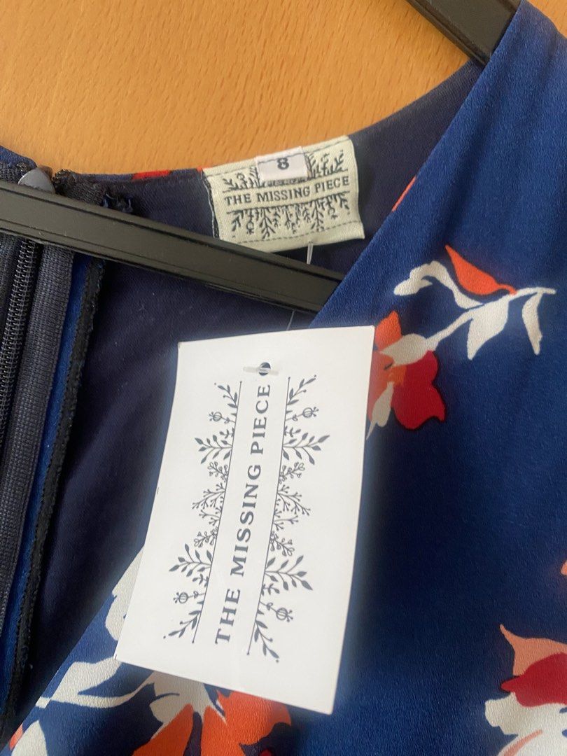 Missing Piece (Category: Dresses) located in Singapore. Submitted by esther21 (Listing ID 1453299541, Image 4). Description: - Brand: The Missing Piece - Size: S (UK 8 / EU 36 / US 4) PTP 41cm Waist 34cm Length 135cm - Color: Navy blue with floral print (red & orange accents) - Style: Midi dress with V-neck, tie-front detail, and waist cut-outs - Condition: Brand new with tags - Perfect for casual outings or events.