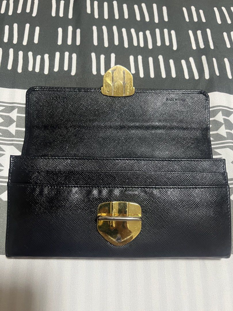 Prada Black Saffiano Leather Long Wallet (Category: Luxury Bags & Wallets) located in Manila. Submitted by yangcastro47434 (Listing ID 1453313590, Image 3). Description: - Authentic Prada wallet in classic black Saffiano leather. - Features a secure gold-tone clasp closure. - Ample card slots and a zippered compartment for organization. - Interior is clean and well-maintained. - Shows minor signs of wear on hardware and edges, consistent with nor