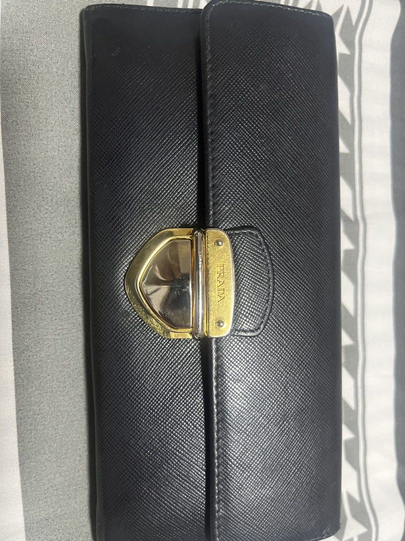 Prada Black Saffiano Leather Long Wallet (Category: Luxury Bags & Wallets) located in Manila. Submitted by yangcastro47434 (Listing ID 1453313590, Image 1). Description: - Authentic Prada wallet in classic black Saffiano leather. - Features a secure gold-tone clasp closure. - Ample card slots and a zippered compartment for organization. - Interior is clean and well-maintained. - Shows minor signs of wear on hardware and edges, consistent with nor