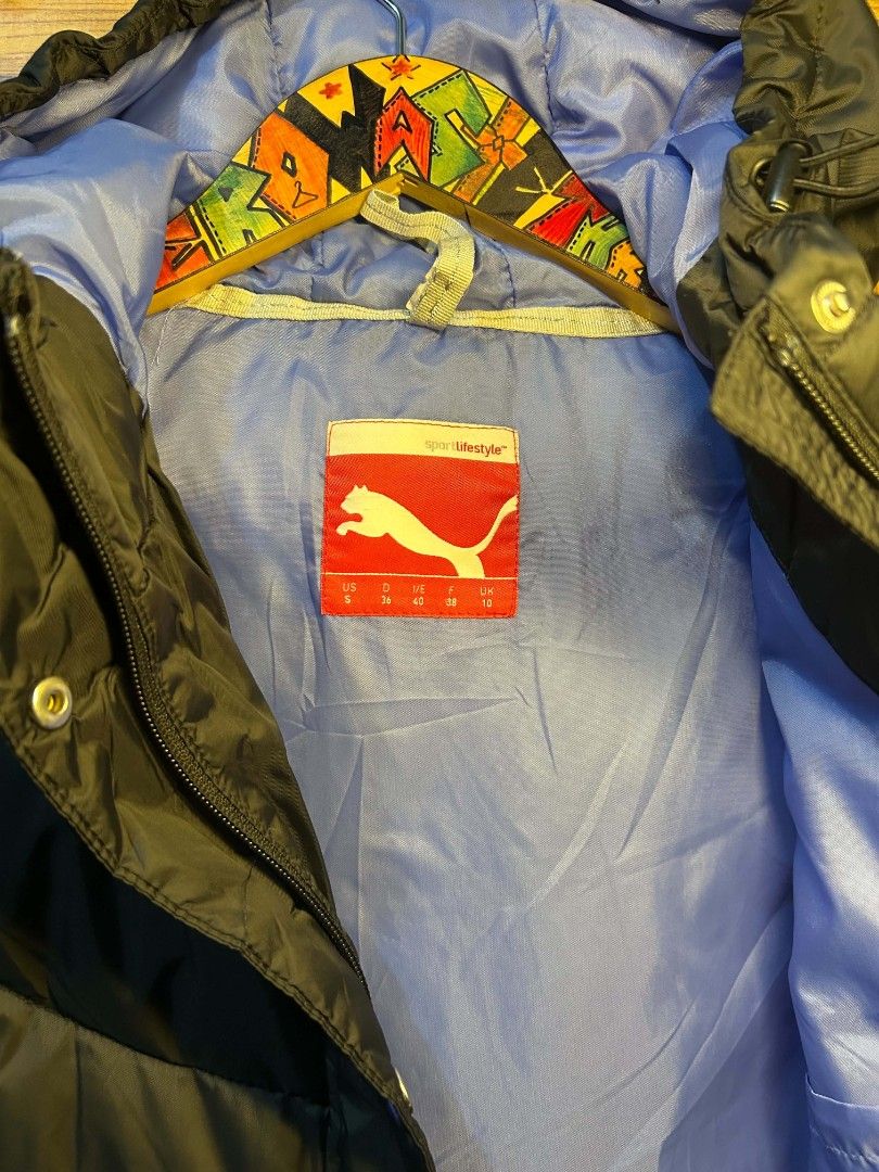 Puma Puffer Jacket (Category: Coats, Jackets and Outerwear) located in Manila. Submitted by zerowastethriftco. (Listing ID 1453411445, Image 3). Description: This is a detailed description of the black Puma puffer jacket: Design & Construction Color: The primary exterior color is a matte black. Quilting: Features a curved, chevron-style baffle pattern on the torso and horizontal stitching along the sleeves. Hood: It comes with an attached, insula
