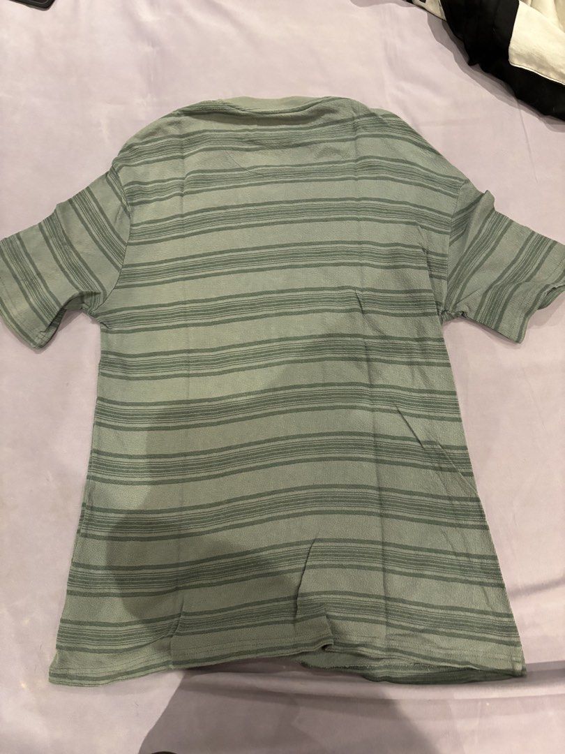 Sage Green Striped T-shirt (Category: Shirts) located in Quezon City. Submitted by digo_bengzon (Listing ID 1453288292, Image 2). Description: - Classic short-sleeved t-shirt - Stylish sage green with darker green horizontal stripes - Comfortable fabric with a subtle texture - Perfect for casual, everyday outfits - Tag visible on the front.