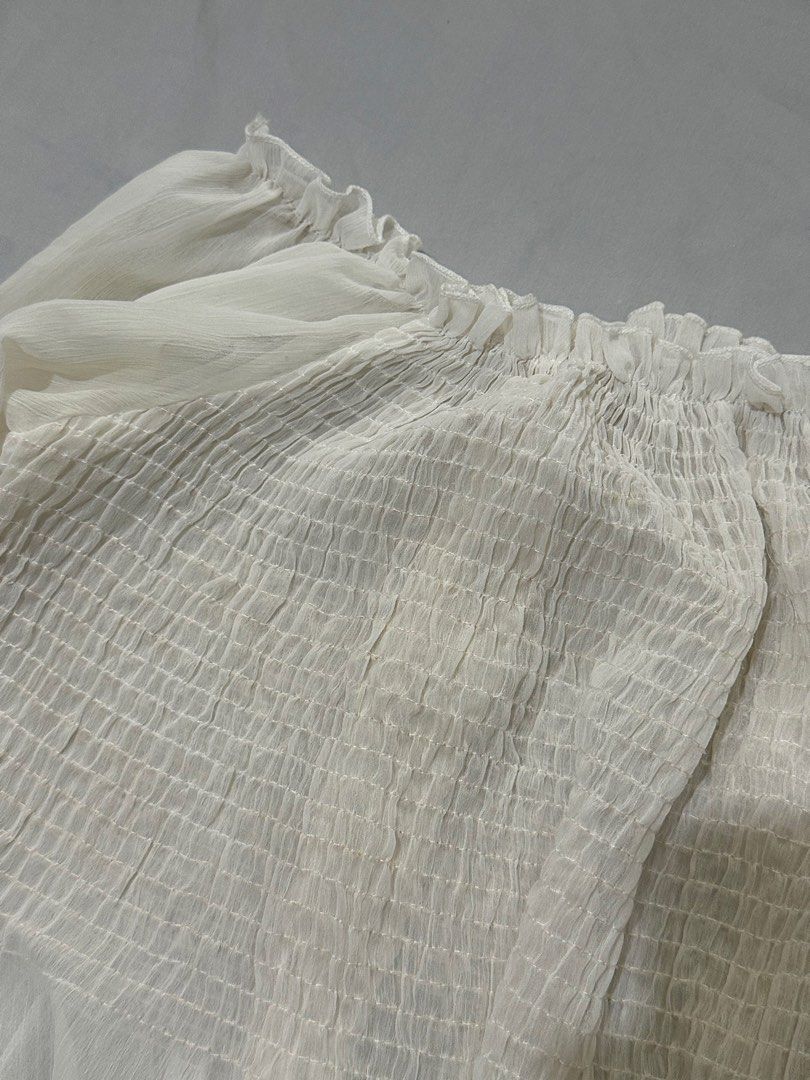 Sheer Off-Shoulder Smocked Crop Top White (Category: Others Tops) located in Pasig City. Submitted by polyhedra_ (Listing ID 1453307060, Image 2). Description: - XS to S - Sheer off-shoulder design - Smocked bodice for a flattering fit - Billowy long sleeves with elastic cuffs - Cropped style - Versatile for dressing up or down - See small cabinet marks (can be removed by laundry).