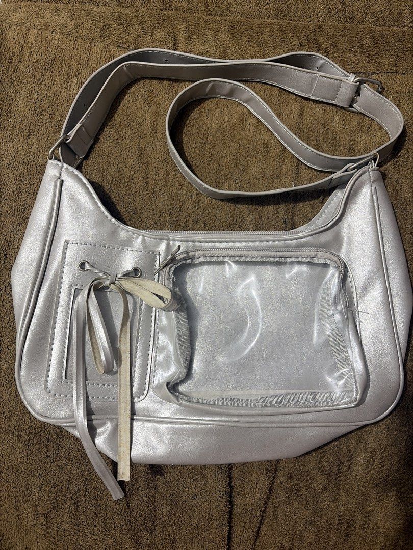 Silver Shoulder Concert Bag with Clear Front Pocket (Category: Shoulder Bags) located in Manila. Submitted by chizym (Listing ID 1453372070, Image 2). Description: - Cool silver shoulder bag - Clear front pocket perfect for displaying pins or charms - Smaller pocket with drawstring closure - Zippered main compartment - Adjustable strap - Ideal for Y2K or streetwear fashion - Needs cleaning.