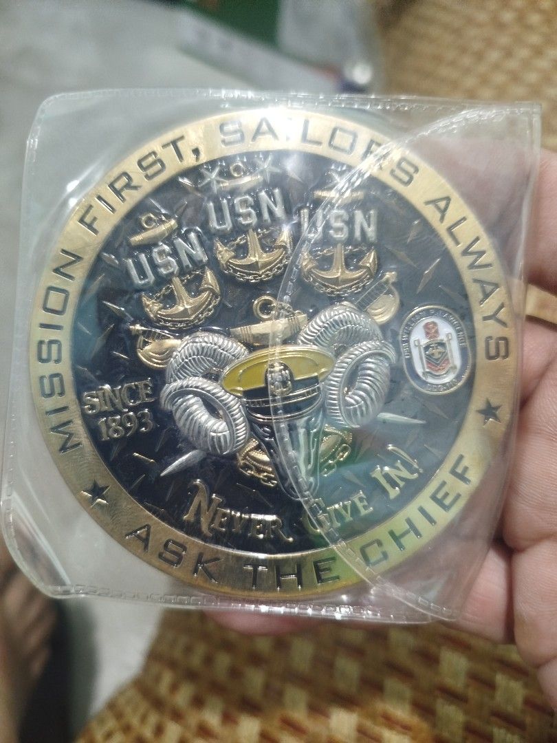US Navy Challenge Coin - Mission First, Sailors Always (Category: Vintage Collectibles) located in Subic. Submitted by regiedaniel01 (Listing ID 1453375092, Image 2). Description: - Double-sided US Navy challenge coin. - Side 1: Hawaiian theme with tiki statues and surfboard. - Side 2: USN anchors, rams' heads, and motto: 'Mission First, Sailors Always, Never Give In! Ask The Chief'. - Ideal collectible for US Navy personnel and enthusiasts..
