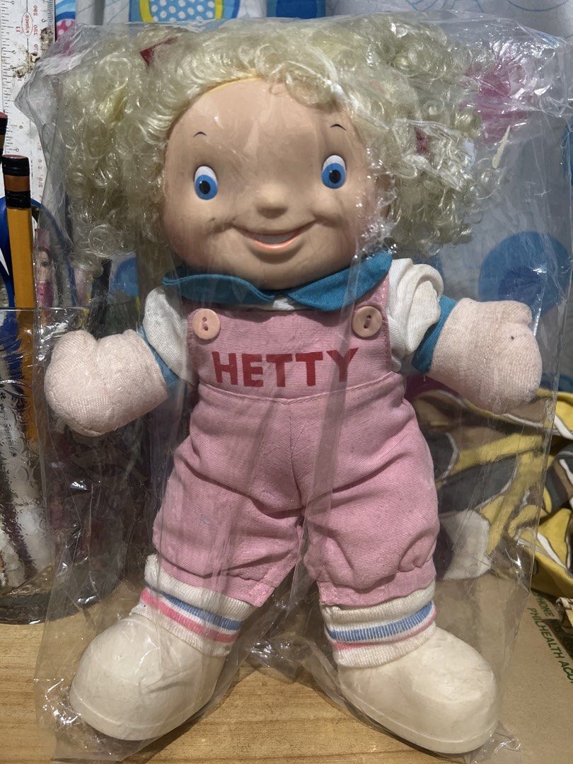 Vintage Hetty Doll in Pink Overalls (Category: Kids Toys) located in Manila. Submitted by semolinapilchard21 (Listing ID 1453336592, Image 1). Description: - Vintage Hetty doll - Original plastic packaging - Pink overalls with 'HETTY' detail - Blonde, curly hair - Blue eyes and big smile - Ideal for collectors and fans of classic toys.