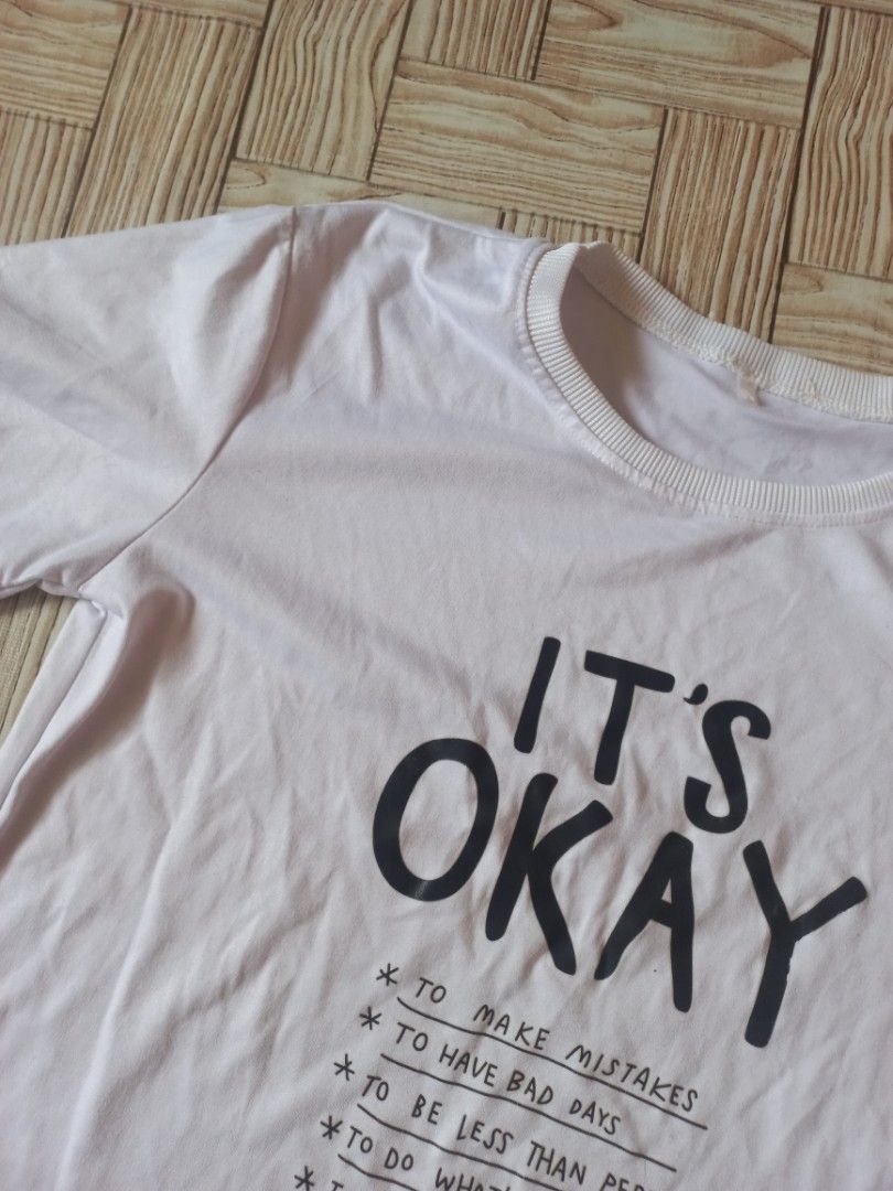 White 'It's Okay' Graphic T-shirt (Category: Tshirts & Polo Shirts ) located in Rizal. Submitted by magi_declutters (Listing ID 1453420011, Image 2). Description: - Classic white crew neck t-shirt - Features a black graphic print with the message 'IT'S OKAY' - Print includes empowering phrases like 'to make mistakes' and 'to be yourself' - Short sleeves for comfortable casual wear - Versatile design, pairs easily with jeans, shorts, or skirts.