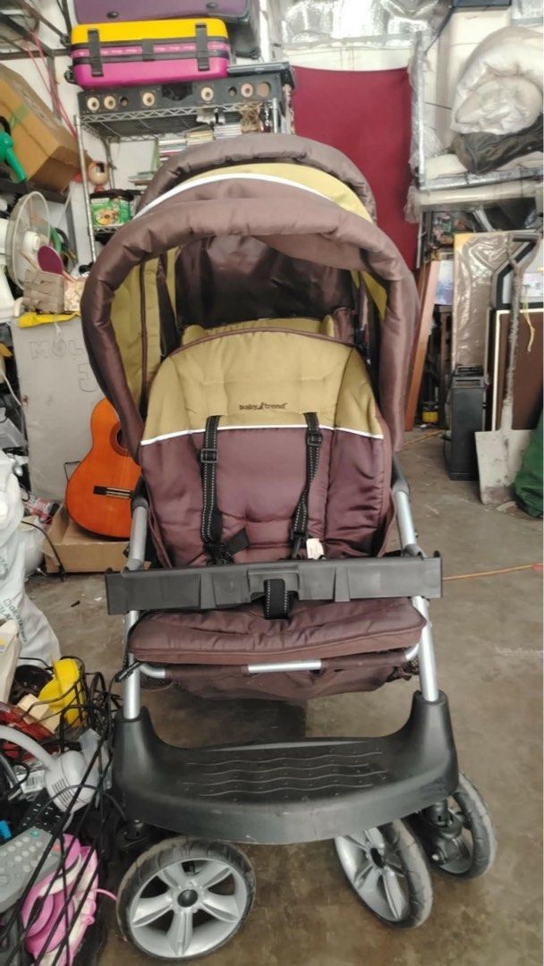Baby Trend Sit-N-Stand Plus Double Stroller (Category: Strollers) located in Calamba. Submitted by rhiajapansurplus-babystuff-03 (Listing ID 1456606165, Image 1). Description: - Sit-N-Stand Plus stroller - perfect for two kids! - Versatile: Front seat for one, rear platform for another to stand. - Stylish brown and tan color scheme. - Convenient cup holder tray. - Spacious storage basket underneath. - Easy to maneuver for smooth rides. - Ideal fo